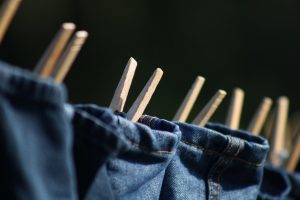 Jeans drying on a clothesline with wooden clothespins.