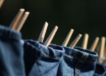 Jeans drying on a clothesline with wooden clothespins.