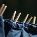 Jeans drying on a clothesline with wooden clothespins.