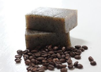 Natural coffee soap bars with coffee beans scattered nearby.