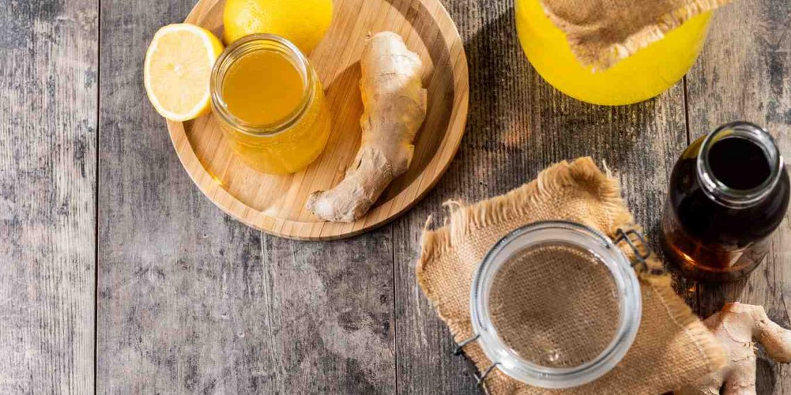Ginger lemon juice with fresh ginger and lemon on a rustic wooden table.