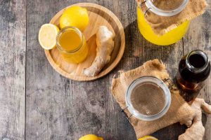 Ginger lemon juice with fresh ginger and lemon on a rustic wooden table.