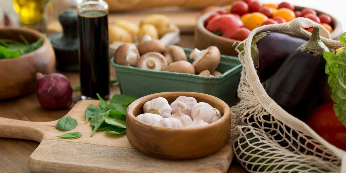 Fresh vegetables and garlic on a wooden table with olive oil.