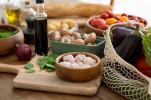 Fresh vegetables and garlic on a wooden table with olive oil.