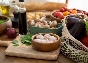 Fresh vegetables and garlic on a wooden table with olive oil.