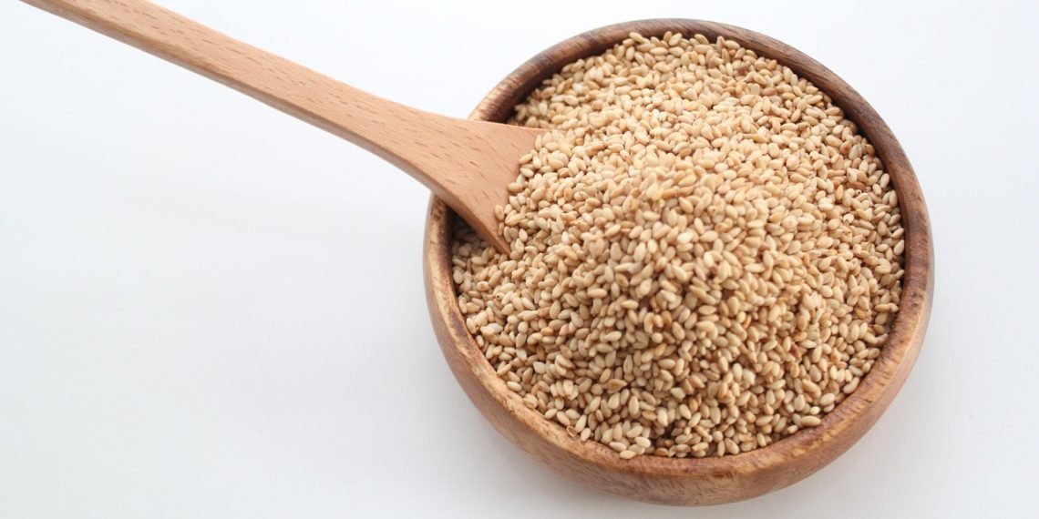 Bowl of sesame seeds with wooden spoon.