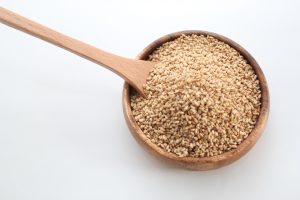 Bowl of sesame seeds with wooden spoon.