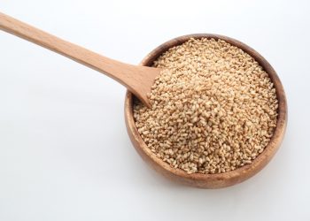 Bowl of sesame seeds with wooden spoon.