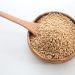Bowl of sesame seeds with wooden spoon.