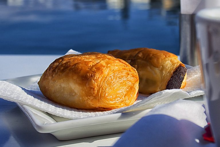 Flaky sausage rolls on a white plate, perfect breakfast snack.