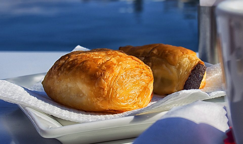 Flaky sausage rolls on a white plate, perfect breakfast snack.