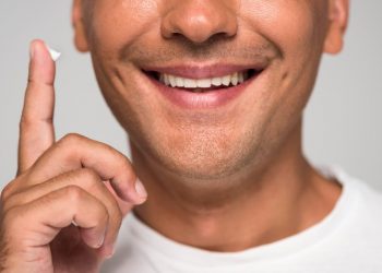 Man smiling, holding cream on finger close to face