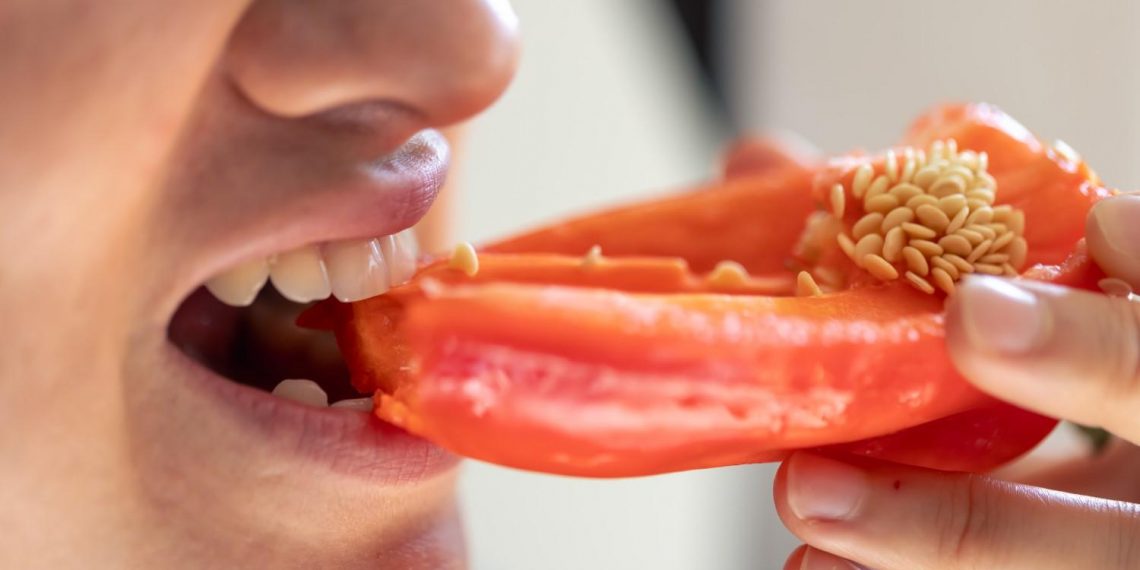 Eating a fresh red bell pepper.