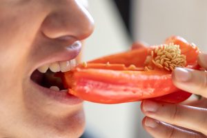 Eating a fresh red bell pepper.