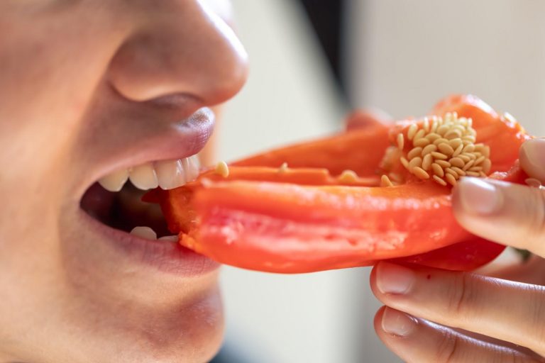 Eating a fresh red bell pepper.