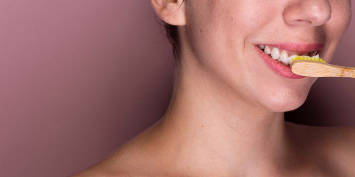 Woman brushing teeth with bamboo toothbrush, promoting oral hygiene