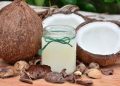 Coconut oil in a glass jar surrounded by fresh coconuts.