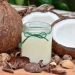 Coconut oil in a glass jar surrounded by fresh coconuts.