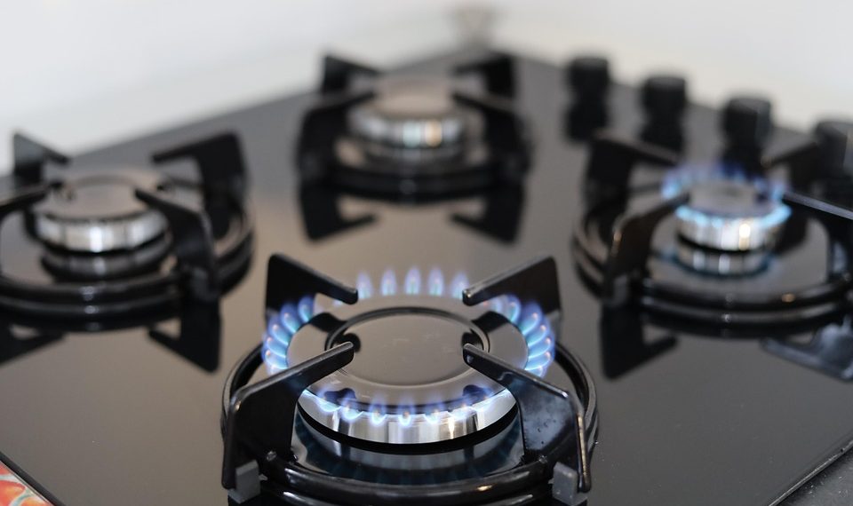 Gas stove burners with blue flames lit for cooking.