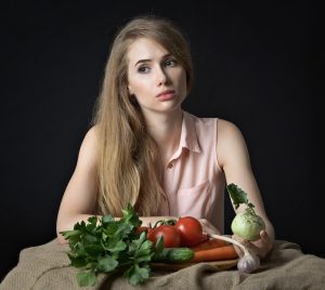 Young woman with fresh vegetables on a table.