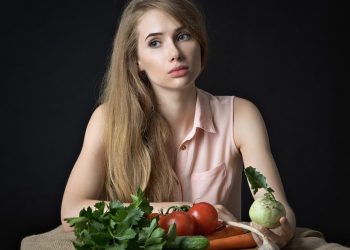 Young woman with fresh vegetables on a table.