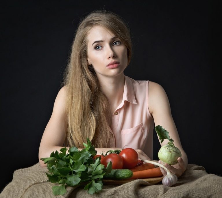 Young woman with fresh vegetables on a table.