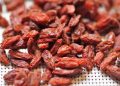 Dried goji berries on a mesh surface.