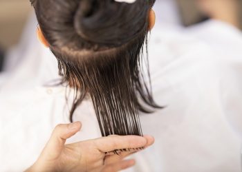 Hair stylist trims wet hair for precise cut.
