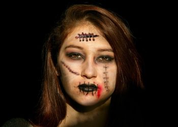 Young woman with horror makeup and stitches on face.