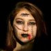 Young woman with horror makeup and stitches on face.