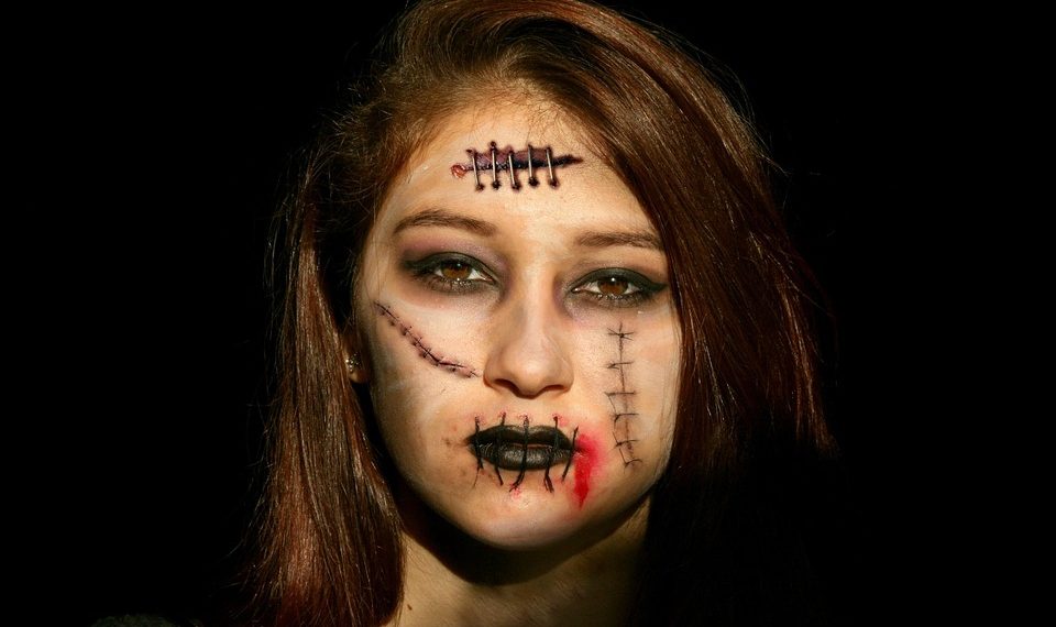 Young woman with horror makeup and stitches on face.