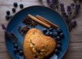 Heart-shaped blueberry scone on plate with spices and lavender.