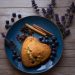 Heart-shaped blueberry scone on plate with spices and lavender.