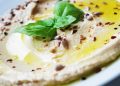 Creamy hummus garnished with basil and seeds.