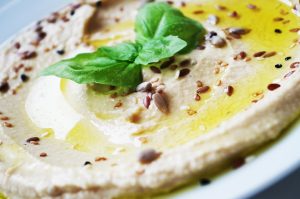 Creamy hummus garnished with basil and seeds.