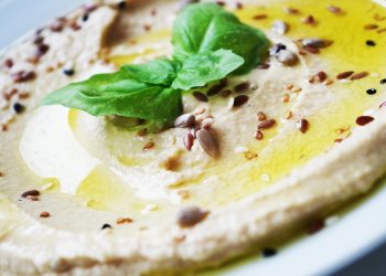 Creamy hummus garnished with basil and seeds.