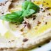 Creamy hummus garnished with basil and seeds.