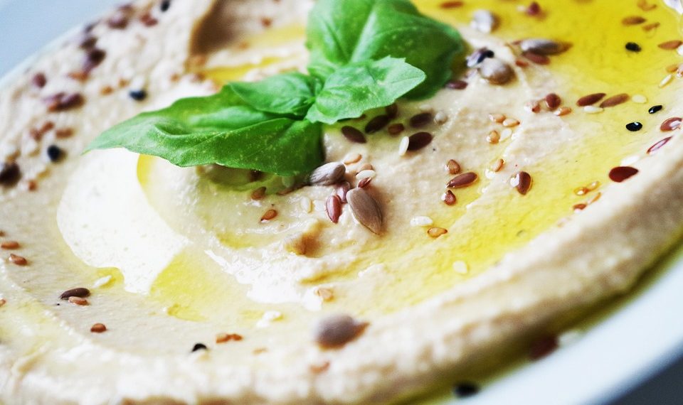 Creamy hummus garnished with basil and seeds.