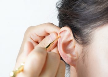 Ear cleaning with golden tool for hygiene maintenance.