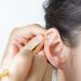 Ear cleaning with golden tool for hygiene maintenance.