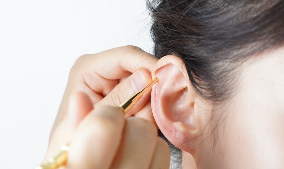 Ear cleaning with golden tool for hygiene maintenance.