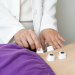 Acupuncture session with needles on patient’s back and practitioner adjusting them.