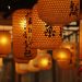 Japanese lanterns with kanji symbols hanging in a row.