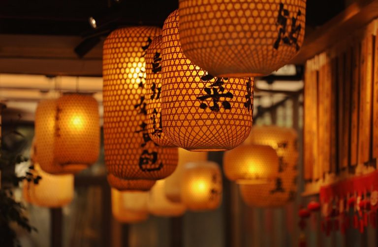Japanese lanterns with kanji symbols hanging in a row.