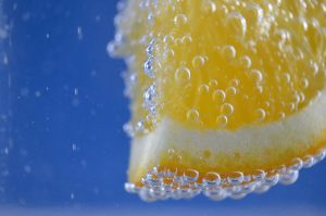 Orange slice with bubbles in water against blue background.