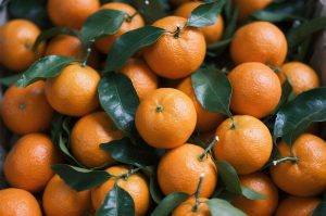 Juicy oranges with green leaves in a basket.