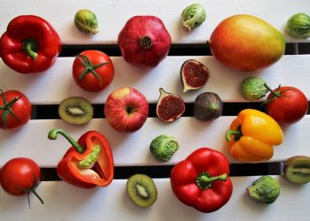 Assorted fruits and vegetables on a white wooden surface.