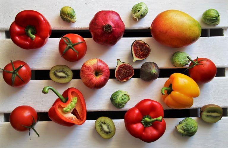 Assorted fruits and vegetables on a white wooden surface.