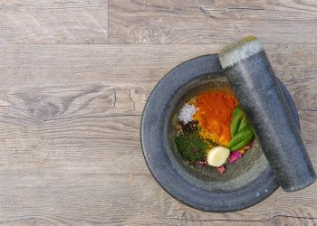 Mortar and pestle with colorful spices and herbs.