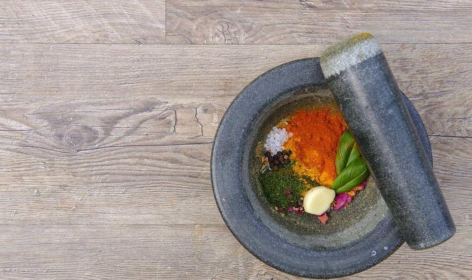 Mortar and pestle with colorful spices and herbs.
